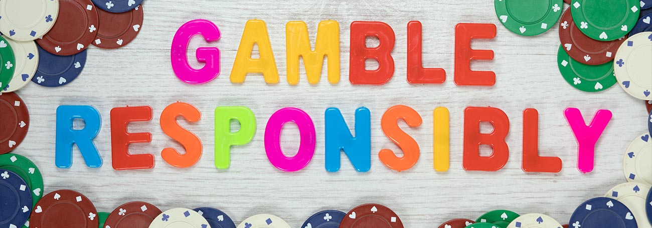 the words gamble responsibly in many colors with casino chips surrounding the words.