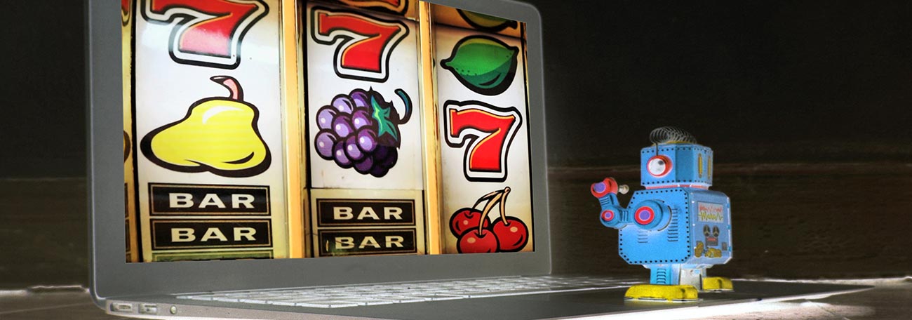 A short robot playing classic slots on his laptop.  The screen shows purple grapes, a yellow pair, a lemon, and three cherries.