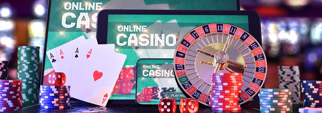 two screens one big one smaller with online casino on the screens with casino chips, cards, roulette wheel, and dice 