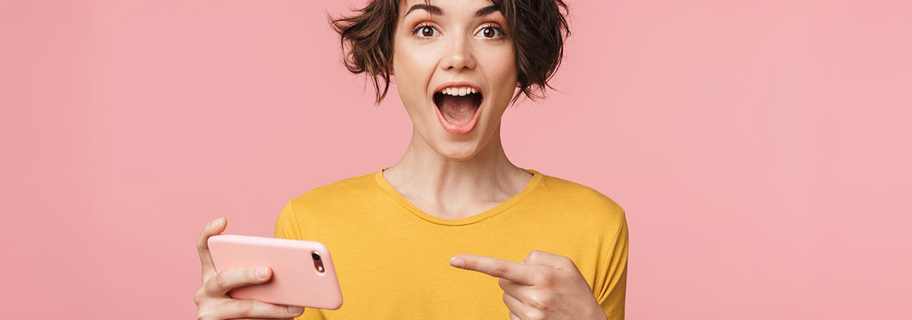 a happy young woman playing on her phone pointing to it to show us