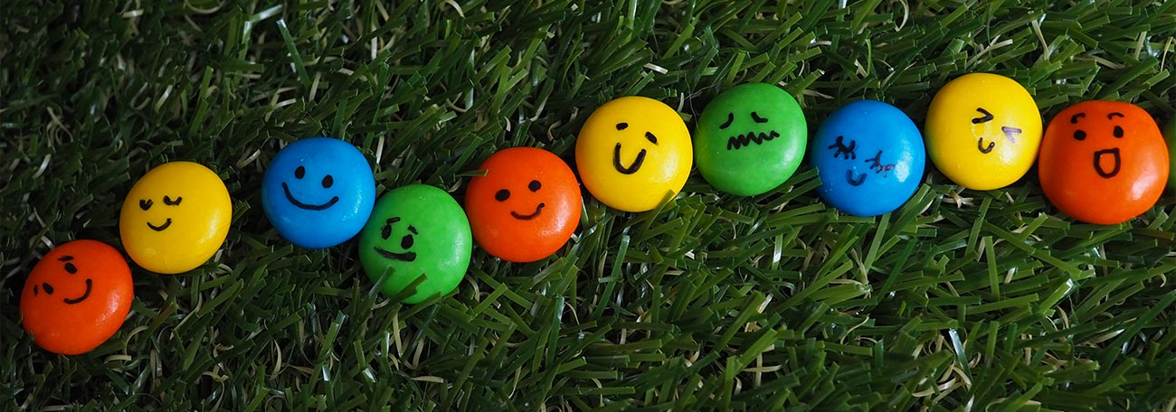 small chocolate candies of different colors with different facial expressions painted on them